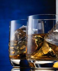 two glasses of whiskey on the table with a bottle