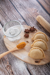 Traditional raw curry puffs stuffed chicken on wooden table as background