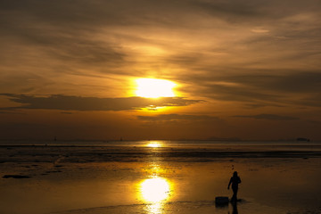 Fototapeta na wymiar Silhouette of man walking on the beach at sunrise