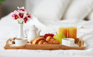 Fototapeta na wymiar breakfast in bed of coffee, croissants, orange juice and fruit on tray