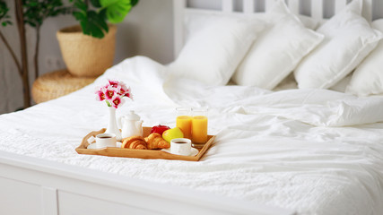 breakfast in bed of coffee, croissants, orange juice and fruit on tray