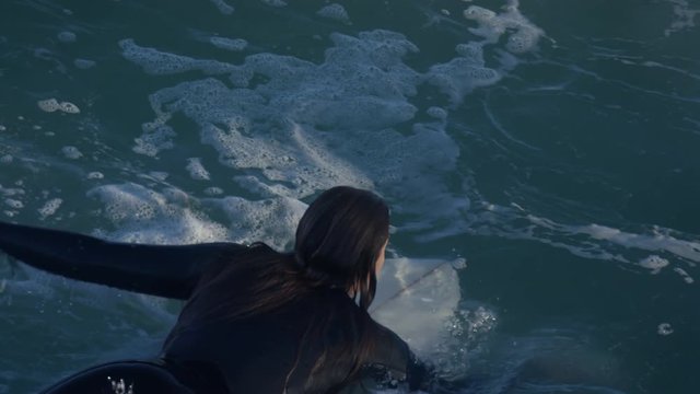 Closeup Aerial View Of Female Surfer Paddling Out To Sea, In Rough Water, Slow Motion