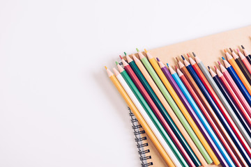 set of wooden colorful pencils on notebook on white background