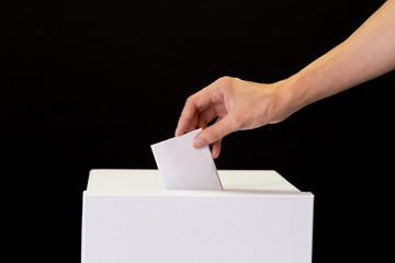 Close-up of human hand casting and inserting a vote and choosing and making a decision what he...