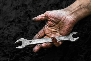 Dirty hand of working man with spanner wrench in car repair workshop