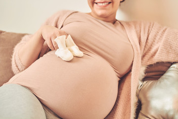 Beautiful pregnant woman touching her belly and enjoying at home.