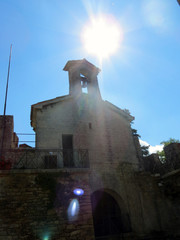 Blinding sun and a chapel with a bell, La Cesta  Tower, Republic of San Marino, Italy.