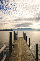 Fototapeta premium Steg am Chiemsee mit Sonnenuntergang und Bergen