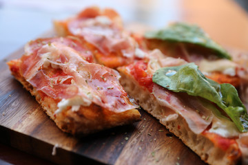 Pizza with parma ham salad rocket and parmesan on dark wooden background close up. Italian food