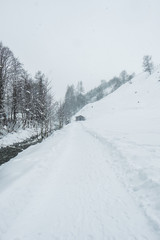 Fototapeta na wymiar Verschneite Winterlandschaft mit Weg und Hütte an einem Bach