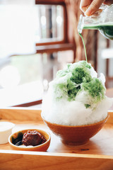Delicious Japanese sweet shaved ice green tea on wooden table in japanese cafe - obrazy, fototapety, plakaty