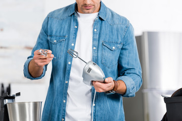 cropped view of man holding kitchen mixer and whisk