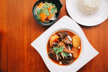Beef massaman curry with rice and salad on wooden background , Thai food