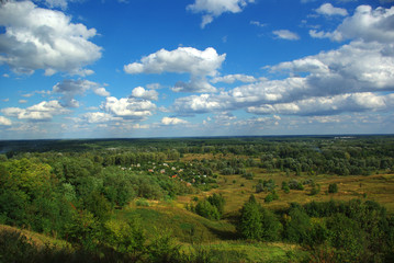 Fototapeta na wymiar Landscape with clouds in the blue sky and forest