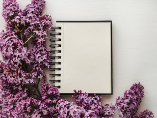 Notepad, blank page for Your inscriptions, bright lilac flowers. Top view, close-up. Preparation for the holiday. Congratulations for loved ones, family, friends and colleagues