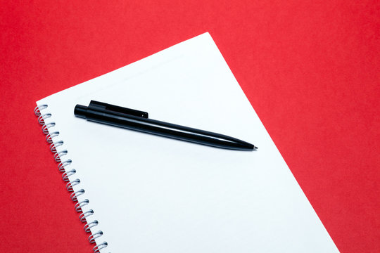 Spring notebook and black pen on blank sheets white paper on red background. Concept of free space, copyspace, business book, notepad, diary, use for notes at art seminar conference, lesson, lecture