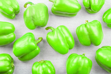 green sweet pepper on white textile background , top view