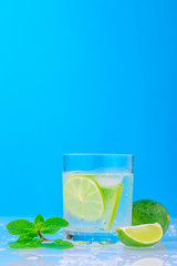 cocktail with lime and fresh mint in glass on a blue background