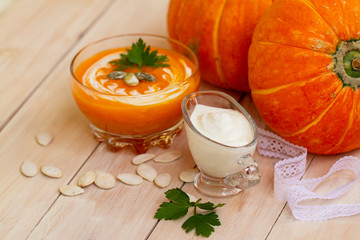 home made pumpkin cream soup with pumpkins and parsley leaves on white wooden table. cream soup of pumpkin