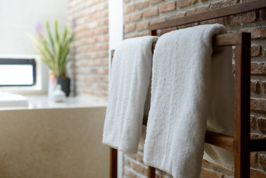 Towels in wooden rack with brick wall background in bathroom