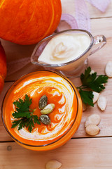 home made pumpkin cream soup with pumpkins and parsley leaves on white wooden table. cream soup of pumpkin. top view