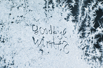 The inscription: goodbye, winter. On a frozen winter window in frosty patterns