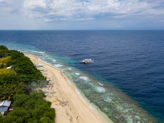 Aerial view of tropical beach on the island Malcapuya. Beautiful tropical island with sand beach, palm trees. Tropical landscape with shore and boats. Palawan, Philippines.