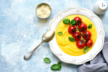 Traditional italian dish polenta with parmesan cheese and grilled tomato.