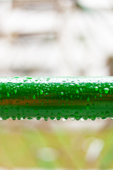 Raindrops on green metal tube. Regentropfen auf Metallrohr.