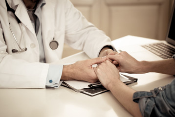 Doctor holding female patient hands with compassion and comfort for encouragement and empathy