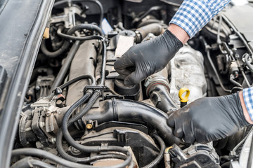 Car engine with worker's hands in gloves