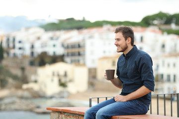 Fototapeta na wymiar Happy man drinking and looking away in a coast town