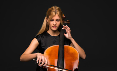 Young girl playing the cello on isolated black background