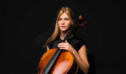 Young girl playing the cello on isolated black background © luismolinero