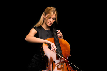 Young girl playing the cello on isolated black background © luismolinero