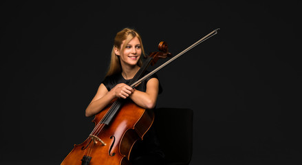 Young girl playing the cello on isolated black background