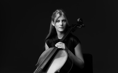 Young girl playing the cello on isolated black background © luismolinero