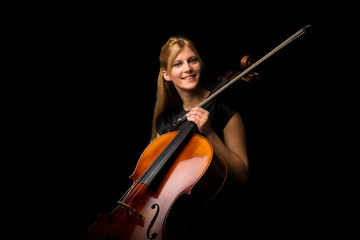 Young girl playing the cello on isolated black background © luismolinero
