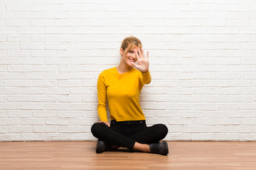 Young girl sitting on the floor counting five with fingers
