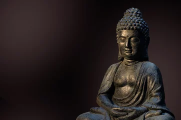 Papier Peint photo Bouddha Statue de Bouddha assis dans une pose de méditation sur fond sombre et profond.
