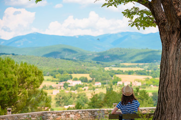Woman on a bench under the tree overlooking valley and mountains in south France