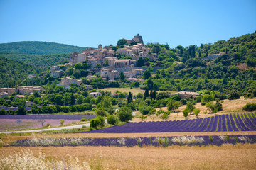 City of Saint-Saturnin-les-Apt on the hill with lavender fields in valley on summer day. Provence, France - obrazy, fototapety, plakaty