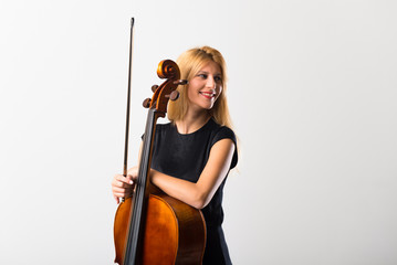 Young blonde girl with her cello posing on white wall © luismolinero