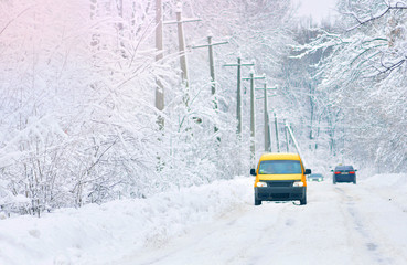 Snow covered road. Yellow car on a snowy road. Winter driving on slippy road.