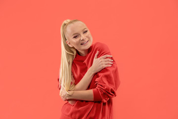 Happy business woman standing and smiling isolated on coral studio background. Beautiful female half-length portrait. Young emotional woman. The human emotions, facial expression concept