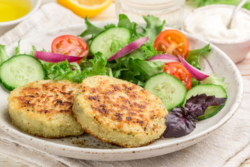 Cutlets (patties ) from white fish (Pollock, cod, perch, pike) in a Plate with lettuce, tomato and cucumber salad. Healthy gourmet dinner. Selective focus
