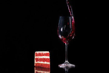 piece cake near glass of red wine isolated on black