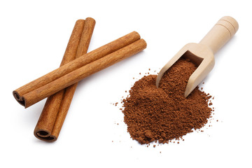 Cinnamon powder in a wooden scoop and cinnamon sticks, isolated on white background