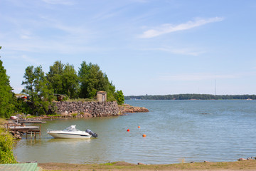 Obraz premium Boat at the wooden pier at the rocky shore on the island of Suomenlinna in the Gulf of Finland in Finland on a summer day.