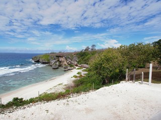 Fototapeta na wymiar Wide distant shot of a white sand beach cove with beautiful blue clouds in a tropical island 